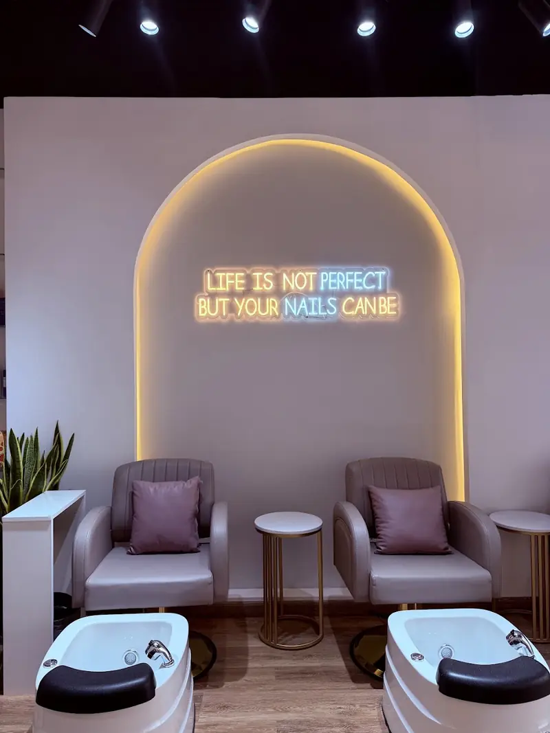 Pedicure lounge under the neon sign 'Life is not perfect but your nails can be'
